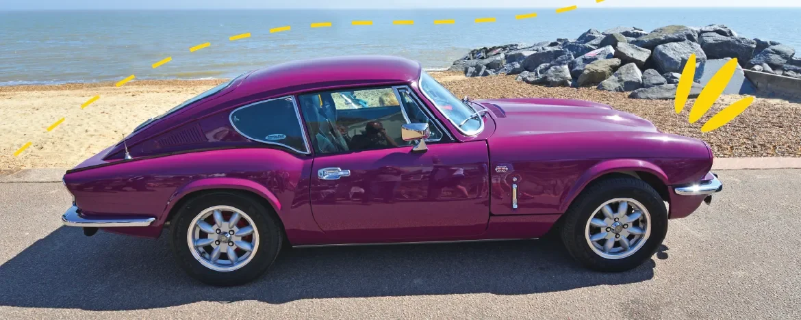 Triumph GT6 in magenta parked at seafront
