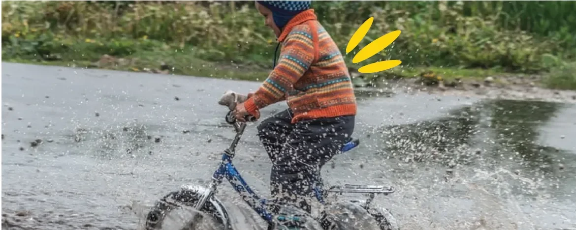 Child on a bicycle riding through a puddle