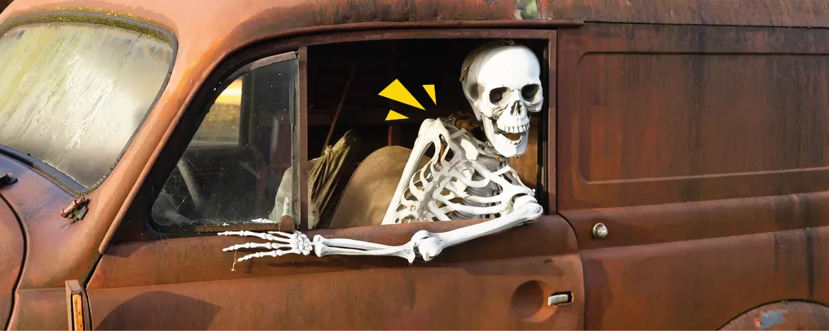 Grinning skeleton in a rusted truck