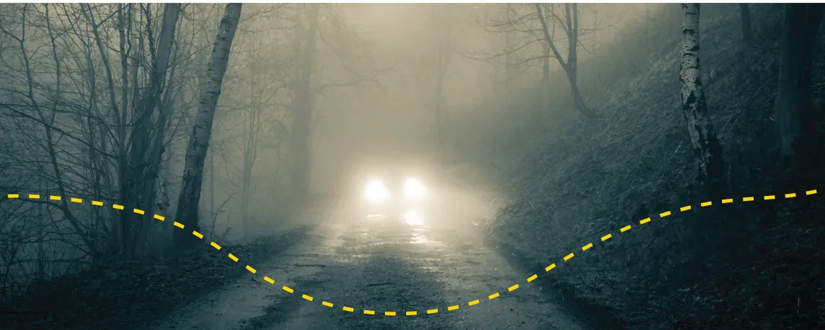 Foggy forest track with car at the end and it's headlights on