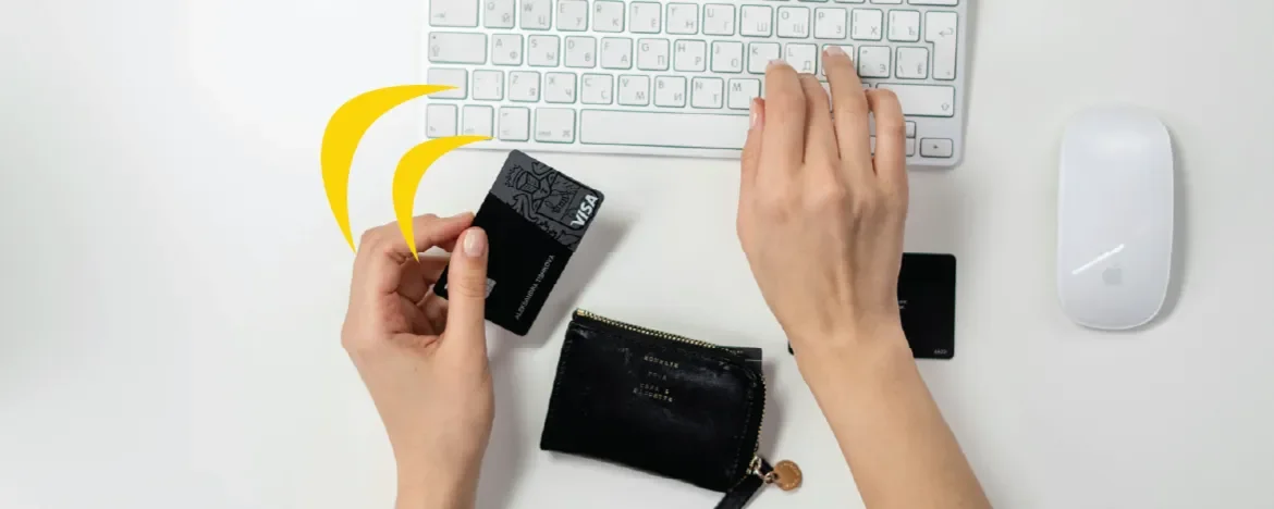 Persons hands on keyboard, holding a credit card