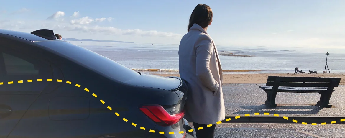 Woman with broken down car at the beach
