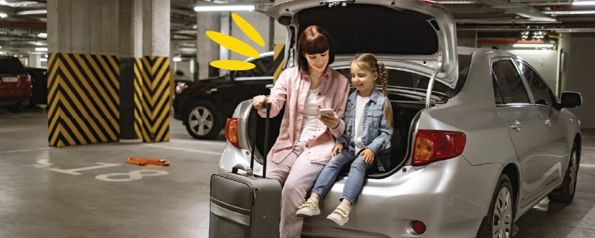 Mother and daughter sit in car boot in airport parking lot