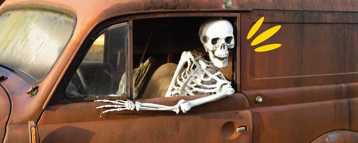 Grinning skeleton sat in a rusted truck