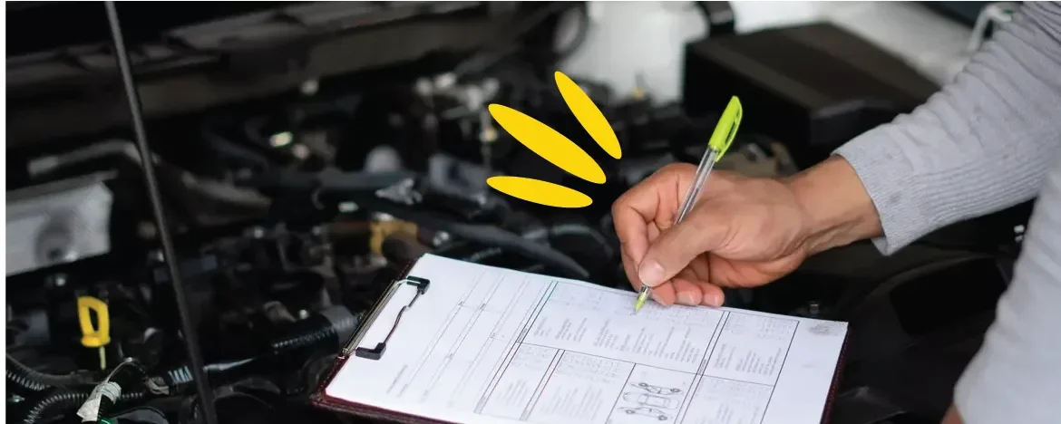 Ticking off a checklist on a clipboard on top of a car engine