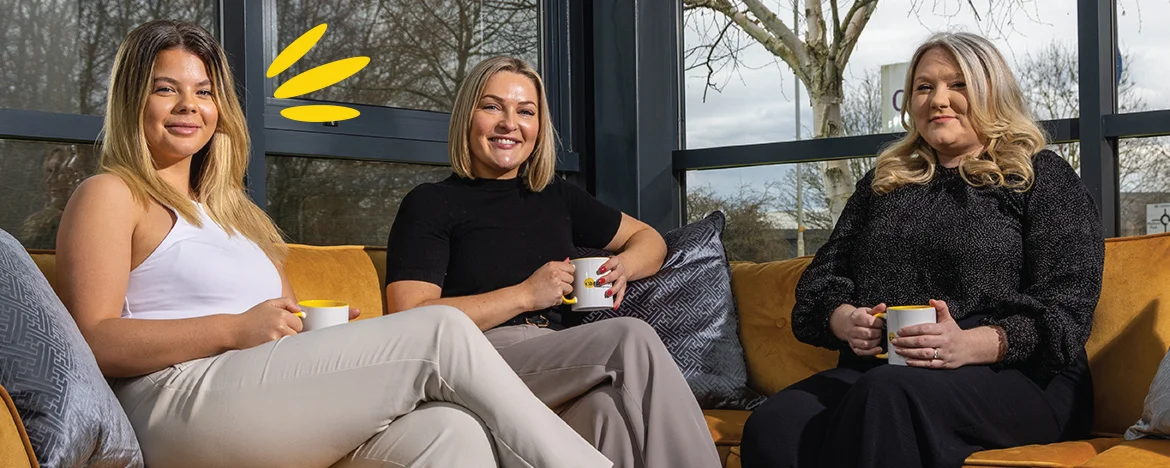 Three female leasing consultants sat on a sofa, smiling.