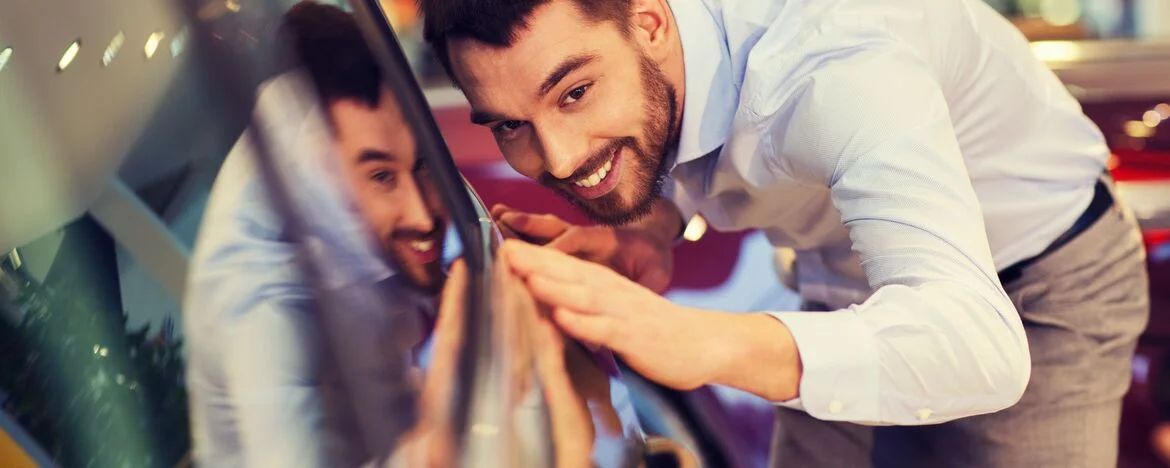 Person smiling while touching shiny, new car