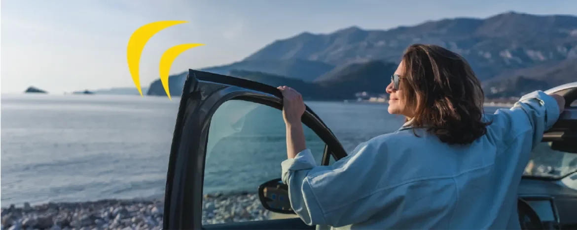 Woman outside car looking at ocean
