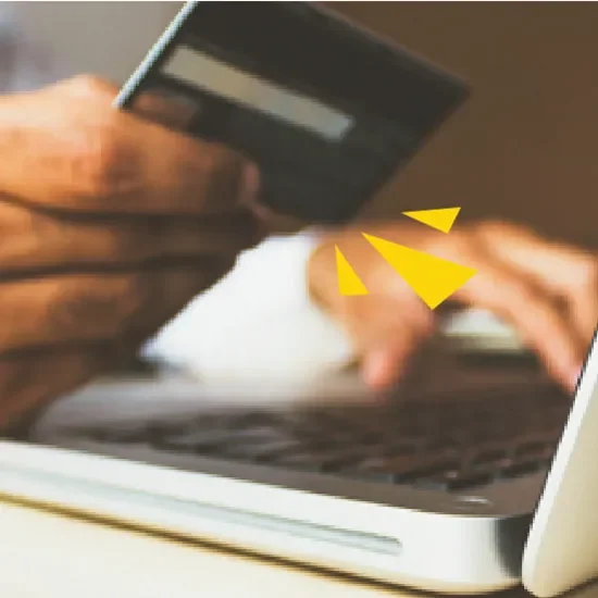 Hand holding credit card over laptop