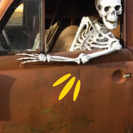 Grinning skeleton sat in rusted truck