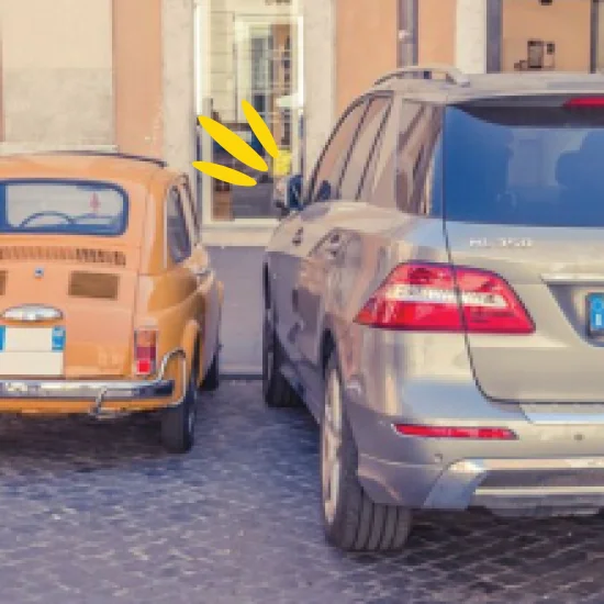 A small retro car parked next to a modern day SUV