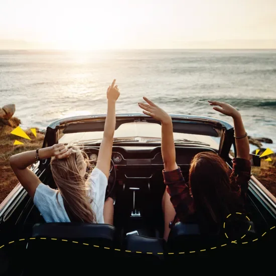 Two people in car with arms in the air