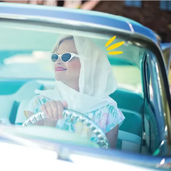 Woman in headscarf driving vintage car